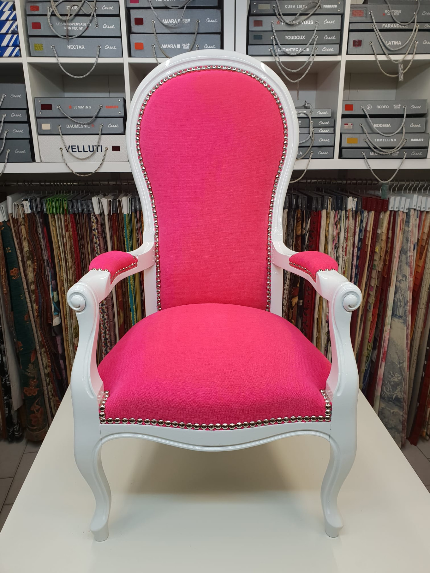 Fauteuil Louis XV laqué blanc capitonné d'un tissu rose fuchsia, restauré par L'Atelier Artisanal